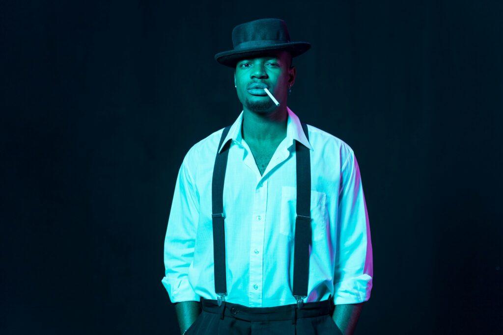 Modern Jazz Confident man with hat and suspenders against dark backdrop, exuding vintage style. blog astuces conseils danses