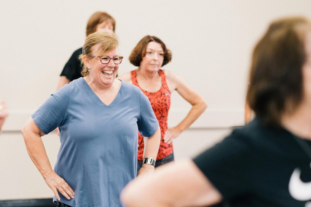Des femmes d'âge mûr, heureuses, participent à un cours de fitness en salle, favorisant la santé et les interactions sociales.