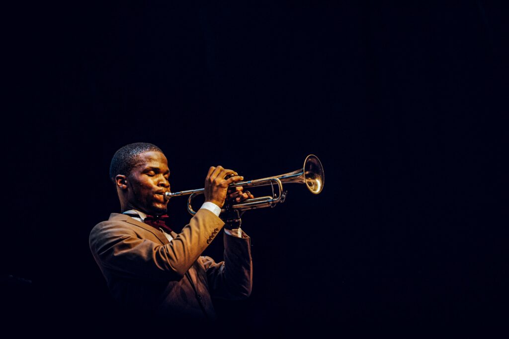 An African man passionately plays the trumpet on stage in Lagos, Nigeria, creating a soulful melody.
