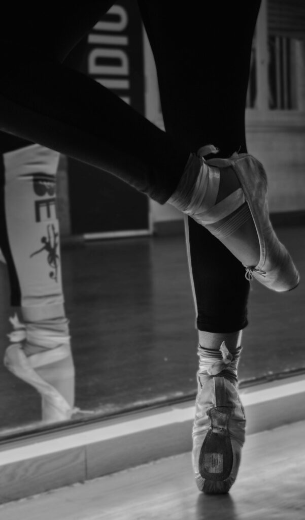 Gros plan monochrome d'une ballerine sur pointes devant un miroir, reflétant grâce et élégance.